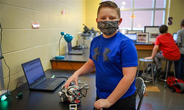 Student stands next to LEGO robot